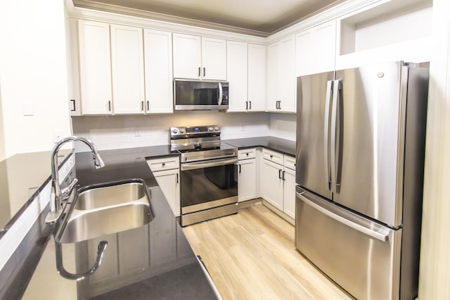 kitchen with white cabinetry, dark countertops, appliances with stainless steel finishes, and a sink