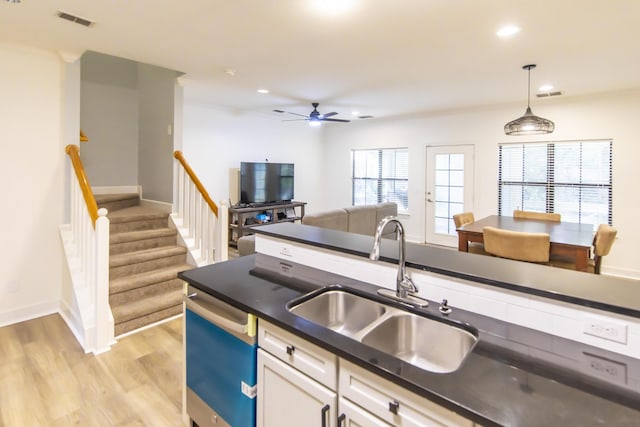 kitchen with a sink, visible vents, dark countertops, and dishwashing machine