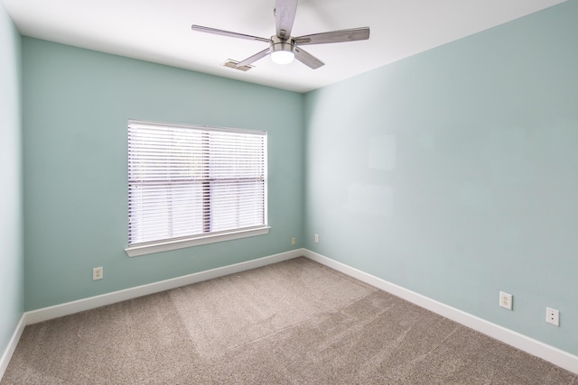 carpeted spare room with a ceiling fan, baseboards, and visible vents