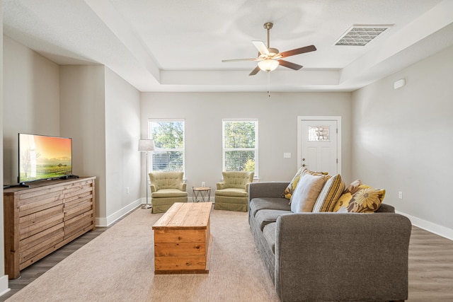 living area featuring visible vents, baseboards, and a tray ceiling