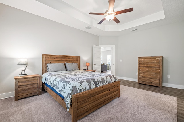 bedroom with visible vents, baseboards, and a tray ceiling