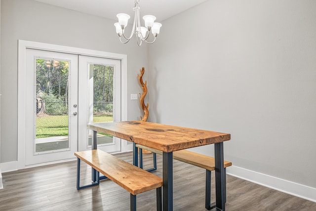 dining space with baseboards, a notable chandelier, and wood finished floors