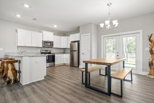 kitchen featuring a notable chandelier, appliances with stainless steel finishes, white cabinetry, and french doors