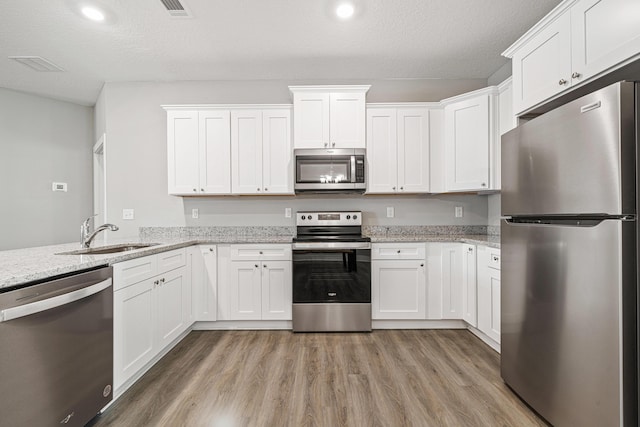 kitchen featuring a sink, light wood-style floors, white cabinetry, and stainless steel appliances