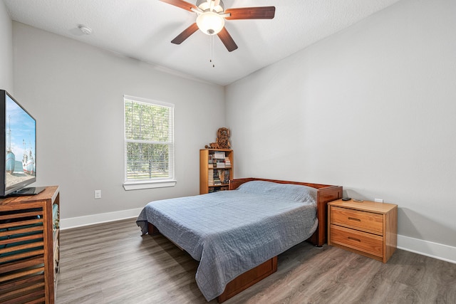 bedroom with ceiling fan, baseboards, a textured ceiling, and wood finished floors