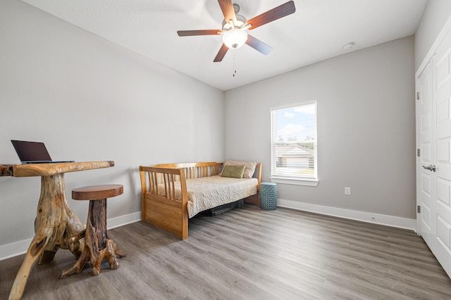 bedroom with a ceiling fan, wood finished floors, and baseboards