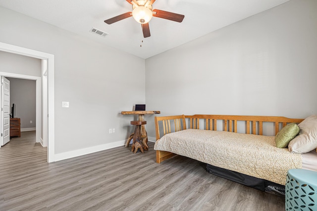 bedroom with visible vents, baseboards, wood finished floors, and a ceiling fan