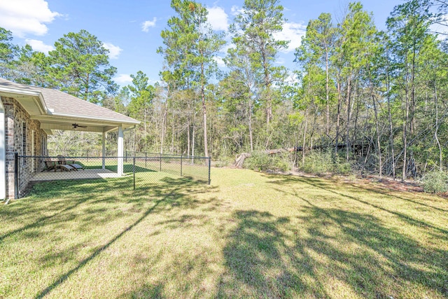 view of yard with ceiling fan and fence