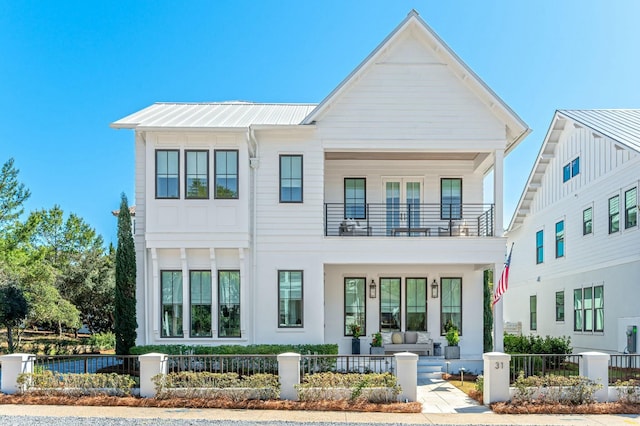 view of front of house featuring a balcony, a fenced front yard, and metal roof