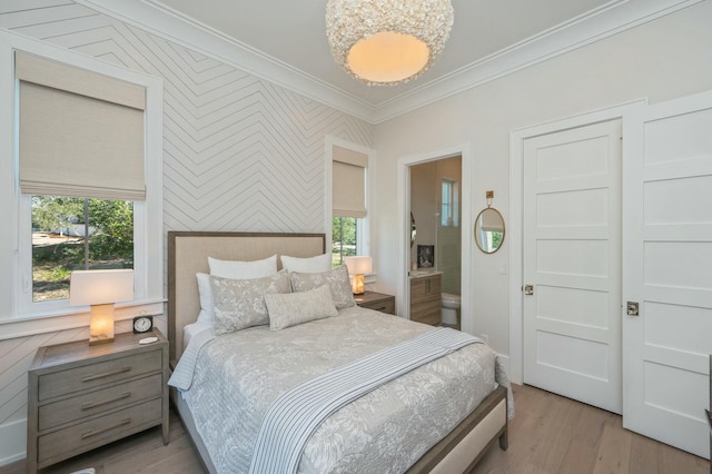 bedroom with light wood-style flooring, connected bathroom, and ornamental molding