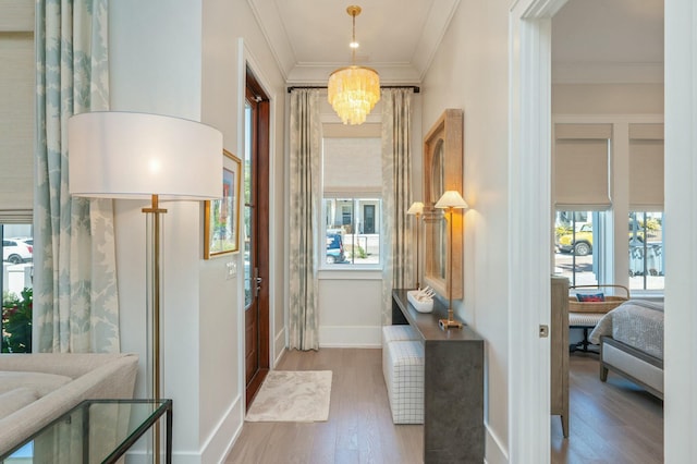 hallway featuring crown molding, wood finished floors, a healthy amount of sunlight, and a chandelier