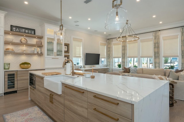 kitchen featuring beverage cooler, open floor plan, light wood-type flooring, and a sink