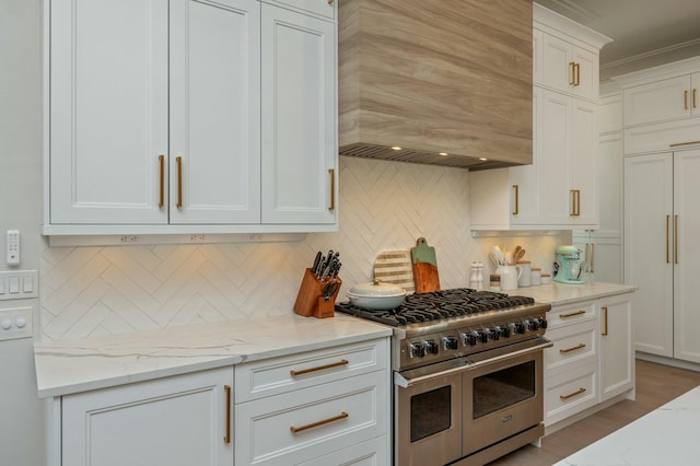 kitchen featuring decorative backsplash, white cabinets, double oven range, and premium range hood