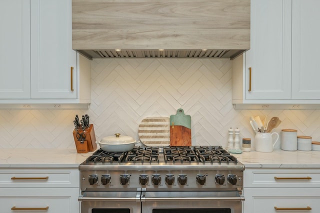 kitchen featuring custom exhaust hood, white cabinets, double oven range, and tasteful backsplash