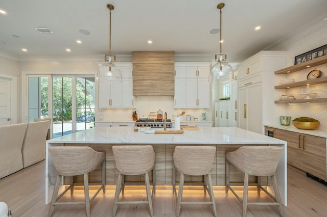 kitchen with custom exhaust hood, ornamental molding, decorative backsplash, white cabinets, and light wood-style floors