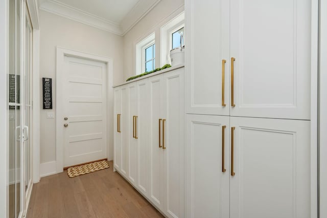 doorway with light wood-type flooring and crown molding