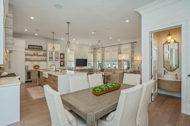 dining area featuring wine cooler, light wood-style floors, and ornamental molding