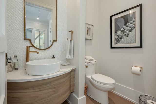 bathroom featuring vanity, toilet, wood finished floors, and tasteful backsplash