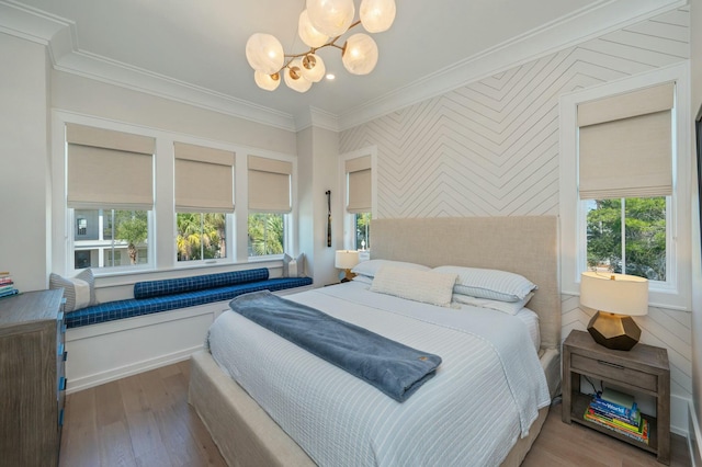 bedroom featuring an inviting chandelier, wood finished floors, and crown molding