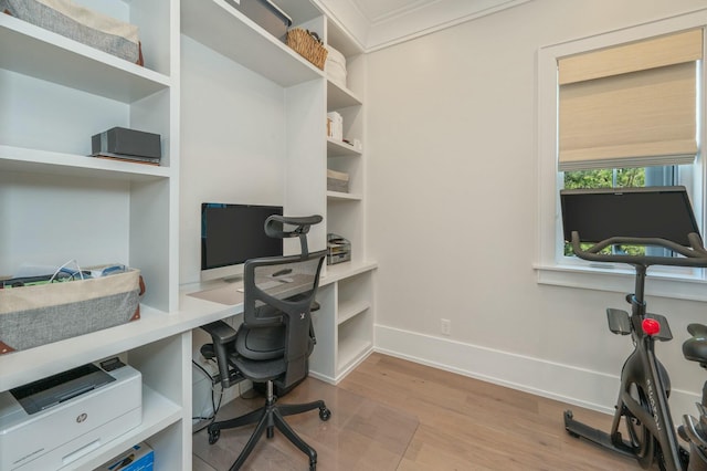 home office featuring baseboards, wood finished floors, and built in desk