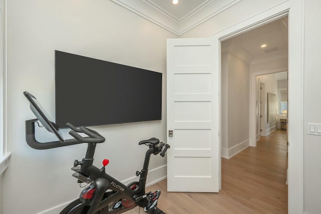 workout room with baseboards, crown molding, and light wood finished floors