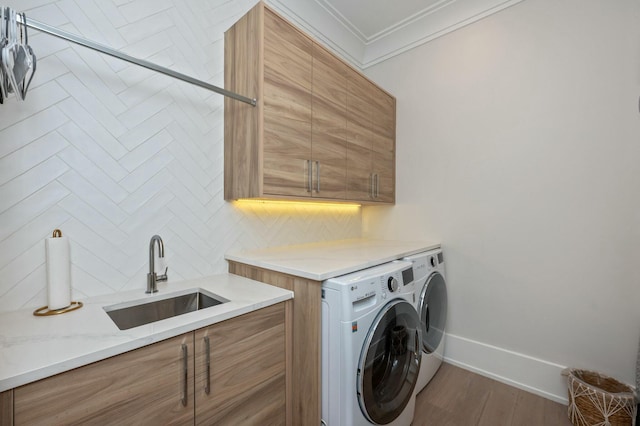 laundry room featuring baseboards, cabinet space, a sink, crown molding, and independent washer and dryer