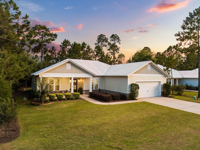 single story home with concrete driveway, covered porch, a lawn, metal roof, and an attached garage