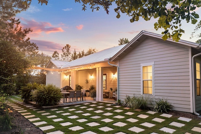 back of house at dusk with metal roof and a patio