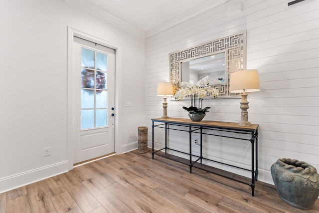 entryway with ornamental molding, baseboards, and wood finished floors