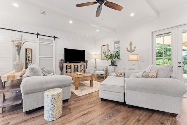 living room with beam ceiling, visible vents, ceiling fan, and wood finished floors