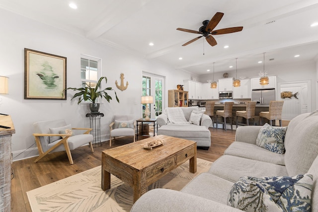 living area featuring beam ceiling, baseboards, ceiling fan, and wood finished floors