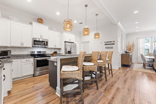 kitchen featuring tasteful backsplash, white cabinetry, light wood-style floors, appliances with stainless steel finishes, and crown molding