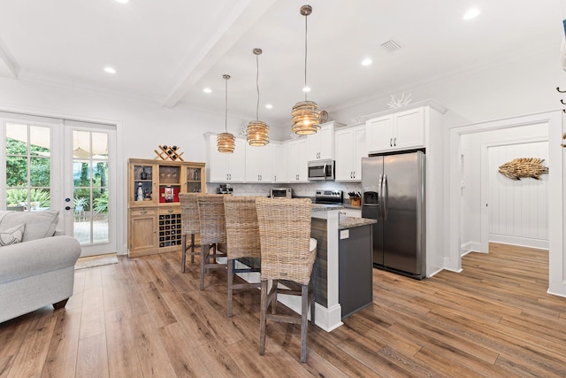 kitchen with visible vents, stainless steel appliances, a kitchen breakfast bar, light wood-type flooring, and backsplash