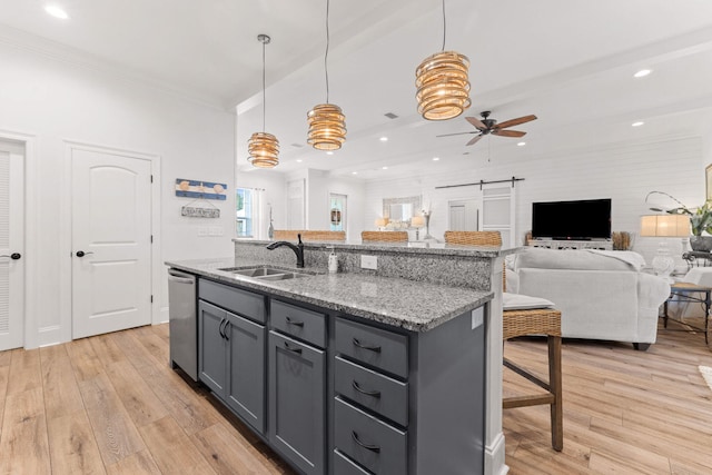 kitchen featuring stainless steel dishwasher, gray cabinetry, light wood-type flooring, and a sink