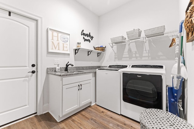 washroom with laundry area, independent washer and dryer, light wood-type flooring, and a sink