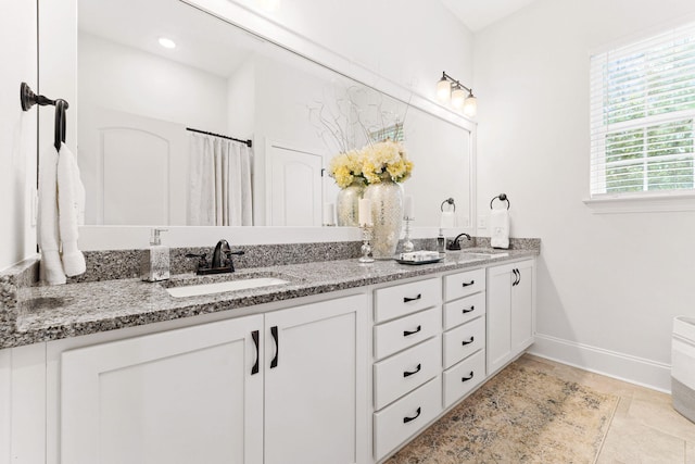 bathroom featuring double vanity, baseboards, tile patterned floors, and a sink