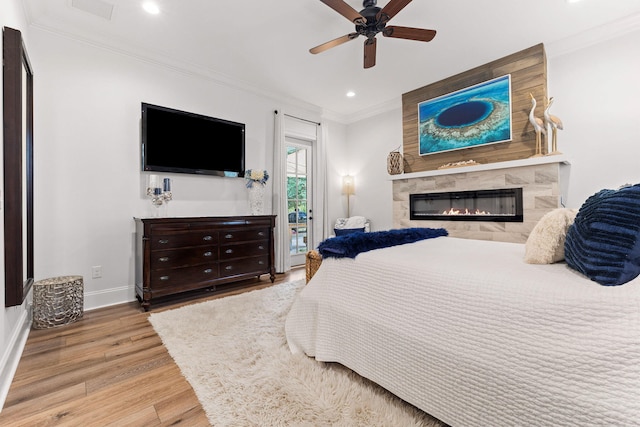 bedroom with access to exterior, visible vents, light wood-type flooring, ornamental molding, and a fireplace