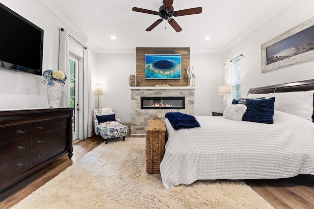 bedroom with a large fireplace, wood finished floors, and ornamental molding