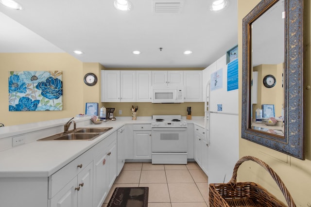 kitchen with visible vents, a sink, white appliances, a peninsula, and light tile patterned floors