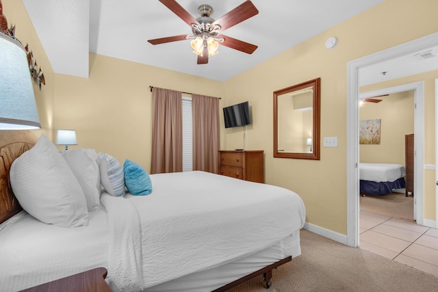 bedroom with visible vents, light carpet, light tile patterned floors, baseboards, and ceiling fan