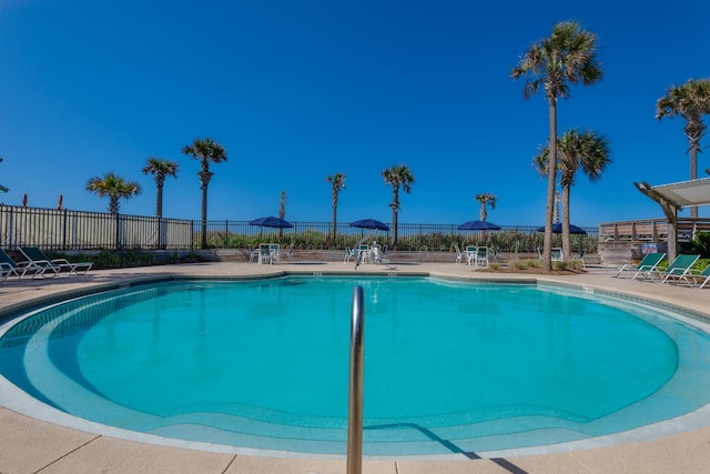 community pool with a patio and fence