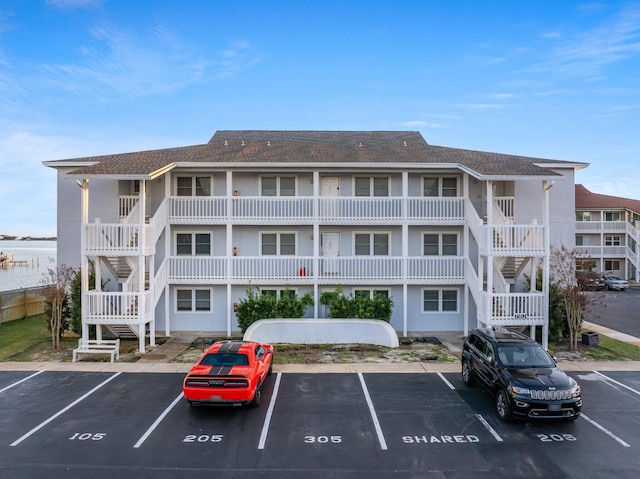 view of building exterior with stairs and uncovered parking