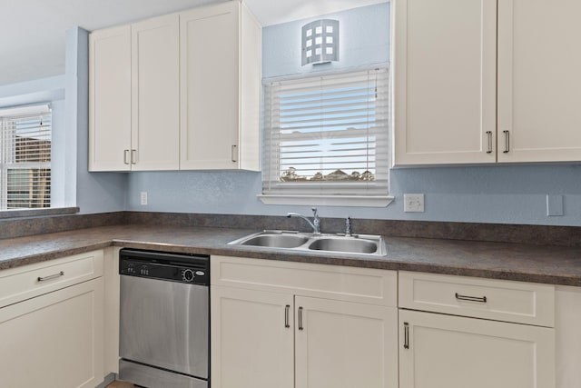 kitchen featuring a sink, stainless steel dishwasher, dark countertops, and white cabinets