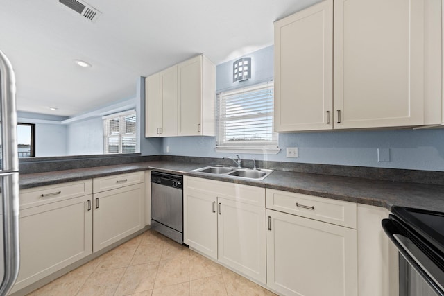 kitchen with stainless steel dishwasher, dark countertops, visible vents, and a sink