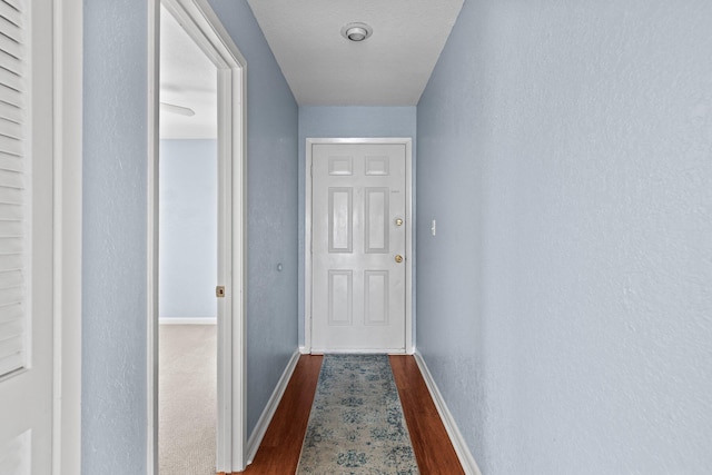 hallway featuring baseboards and dark wood-style flooring