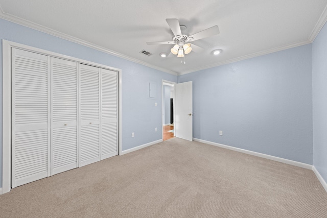 unfurnished bedroom featuring a closet, crown molding, baseboards, and carpet floors