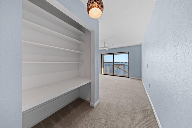 hallway with a textured wall, built in features, baseboards, and carpet floors