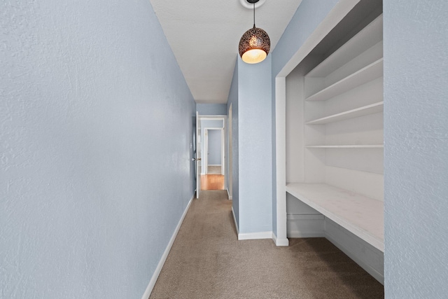 corridor featuring baseboards and dark colored carpet