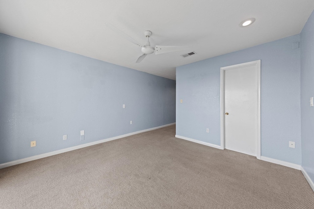 spare room with a ceiling fan, visible vents, carpet floors, and baseboards