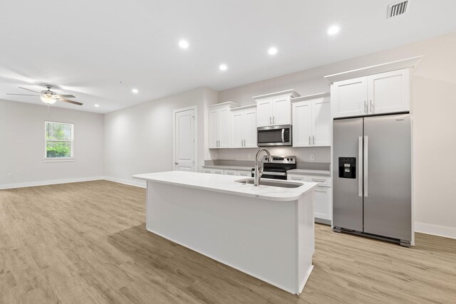 kitchen featuring stainless steel appliances, a sink, a kitchen island with sink, white cabinets, and a ceiling fan